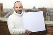 © Anne-Marie Albrecht - Portrait of a man holding a blank sheet of paper on the roof