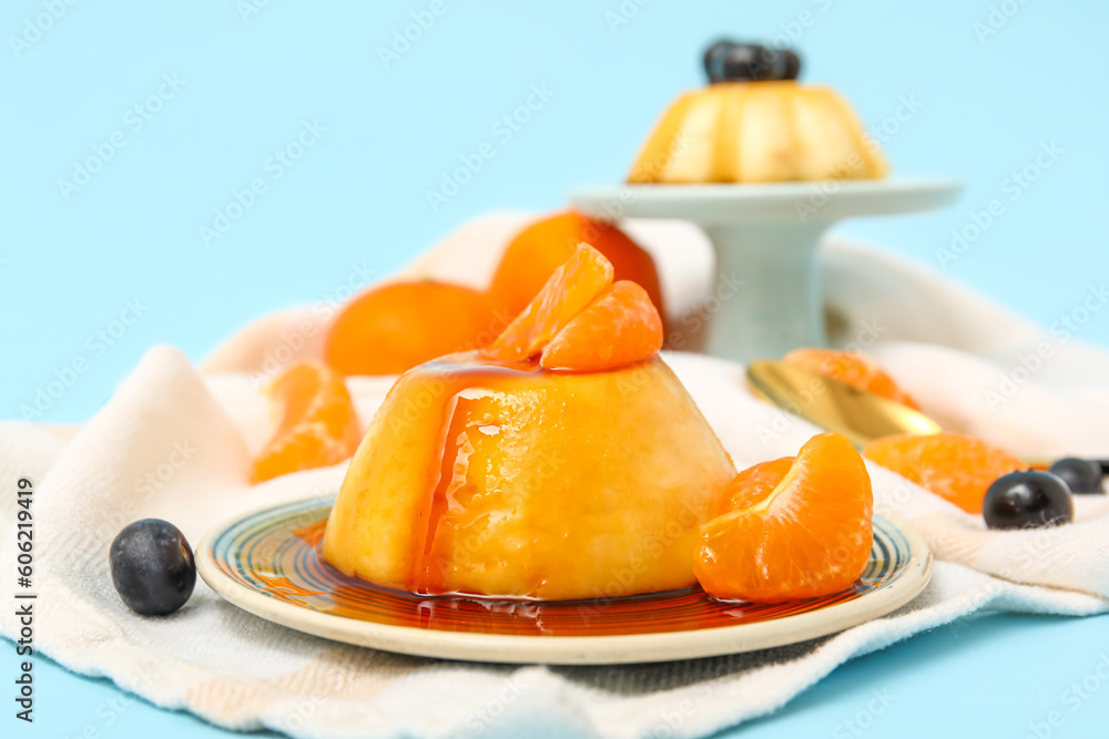 Delicious pudding, tangerines and blueberries covered by caramel syrup on blue background