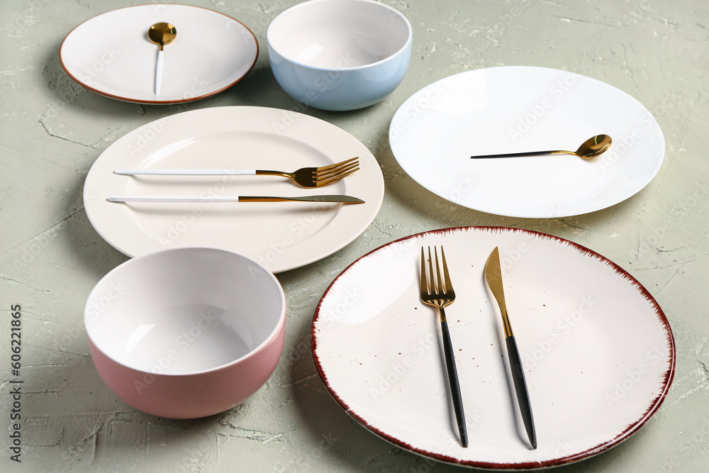 Table setting with clean plates, bowls and cutlery on grey grunge table