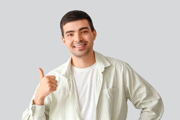 Poster - Young man showing thumb-up on light background