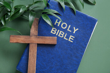 Holy Bible with branches and cross on green background