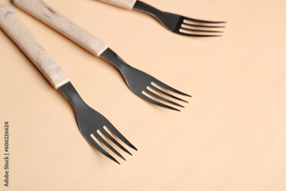 Stylish forks on beige background