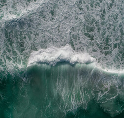 Canvas Print - Aerial view of a wave in the ocean with surfers nearby