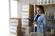 Serious young female volunteer holding clipboard in a large warehouse, working in charity center. donation and volunteering