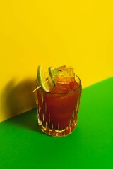 Vertical shot of a Vampiro cocktail with green and yellow background