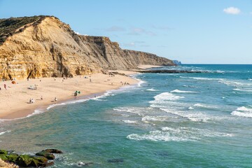 Poster - Scenic view of the Sao Juliao beach in Sintra,Portugal from a cliff with people sunbathing on shore