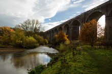 High Arched Stone Bridge Over A River With Autumn Trees In A Park