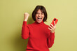 © kegfire - Excited young female with smartphone shouting while celebrating success