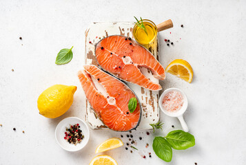 Wall Mural - Fresh raw salmon steaks with spices, lemons and pink salt on white wooden board. Top view of fish on white background. Keto recipe.