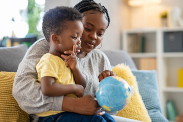 Mother showing a world globe to a cute toddler son. Early education