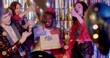 © Alena - Friends give birthday present to smiling Afro guy during party. Celebration atmosphere. Happiness to be surrounded by loved ones and receive attention during the holidays. Applause and confetti.