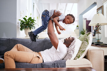 Canvas Print - Black family, airplane and father with son on a sofa with love, lifting and playing in their home together. Flying, child and fun with parent on sofa, laugh and play, bonding and games in living room