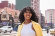 © ADDICTIVE STOCK - Smiling black woman standing on city street
