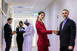 © kanpisut - Diverse friend partners colleagues talking walking in modern office hallway. Confident business partners walking down in office building and talking. Professional business people walking and talking