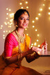 Beautiful Hindu Indian young women lightening deepa on Diwali day.