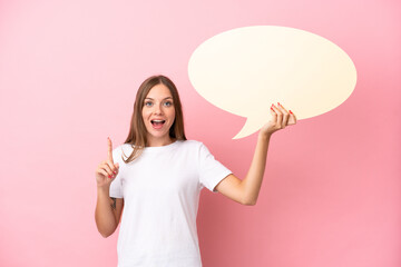 young lithuanian woman isolated on pink background holding an empty speech bubble with surprised exp
