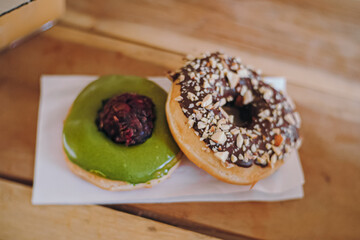 two sweet donuts on a white plate, chocolate peanut and green tea