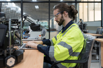 Male engineer using laptop computer for training Programmable logic controller. Programmer create programmable computer for control AI robot in the robotics room