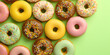 Top view of delicious vanilla doughnuts with colored glaze isolated on a flat grass green surface background. Creative wallpaper with donuts. Generative AI professional photo imitation.