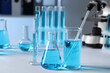 © New Africa - Different laboratory glassware with light blue liquid on table