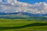 Fototapeta Góry - Picturesque foothill valley and snow-covered peaks on a spring evening