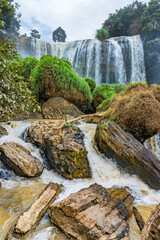 Wall Mural - Water flowing around large rocks at the base of a waterfall at Elephant Falls in Vietnam