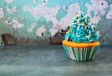Horizontal Close Up Blue Iced Cupcake Decorated With Sprinkles On A Blue Background