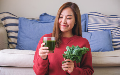 Wall Mural - Portrait image of a young woman holding kale leaves and kale smoothies