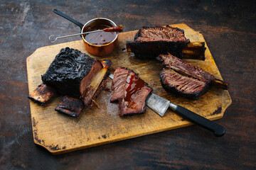 Wall Mural - Traditional barbecue burnt chuck beef ribs marinated with spicy rub and served as close-up on a rustic wooden board