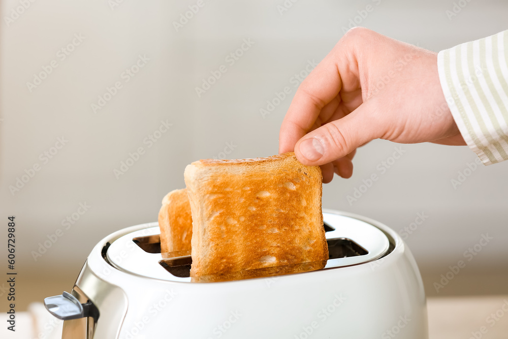 Man taking crispy bread slice from modern toaster, closeup