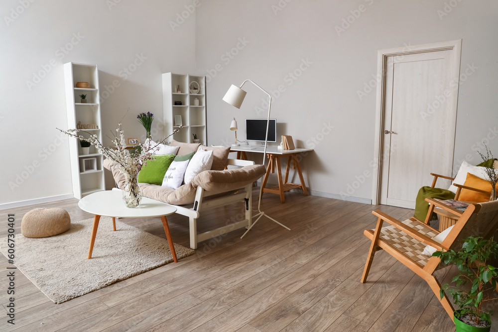 Interior of living room with grey sofa and blossoming tree branches on table