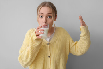 Poster - Young woman drinking milk on grey background