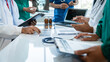 © Ratirath - Medical surgical team meeting with doctors in white lab coats and surgical gowns sitting at table discussing x-ray of patient history. success of medical health care.