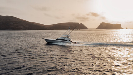 Poster - Sport fishing boat in profile against a backdrop of rugged mountainous shores