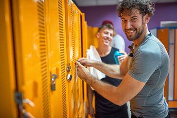 Young man in sportswear locking his locker in the dressing room, ready for workout.