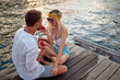 © luckybusiness - A young couple is sitting on the dock on the seaside and enjoying a juicy watermelon. Love, relationship, holiday, sea