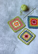Colorful crochet Granny squares on light grey background with copy space. Handmade blanket in process. Multicolored vintage ornament. Hippie fashion concept. 