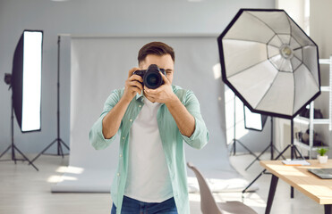 Male photographer shooting in studio with professional lighting equipment. Portrait of professional freelance photographer taking photo with professional digital camera