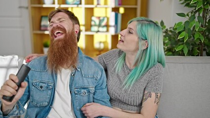 Poster - Man and woman couple singing song using remote control as a microphone at home