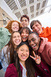 © CarlosBarquero - Vertical multi-ethnic group smiling student boys and girls taking selfie outdoors. Happy lifestyle concept of friendship in multicultural young people having fun day together. Seven partners enjoying.