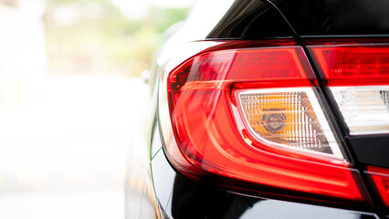 Wall Mural - Close up tail light of black car. In the pakring lot. with abstract and blurred of background with sunlight.