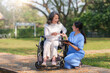 © amnaj - Asian nurse or physiotherapist caring for elderly woman sitting wheelchair. Asian female nurse takes care of patients and takes them for a walk in the hospital park.
