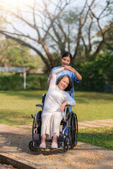 Wall Mural - Asian nurse or physiotherapist caring for elderly woman sitting wheelchair. Asian female nurse takes care of patients and takes them for a walk in the hospital park.