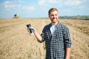 Wall Mural - Young farmer in wheat field during harvest in summer