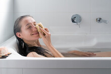 Relaxed Woman Washes Herself With A Loofah Washcloth. Concept Of Self-love And Self-care.
