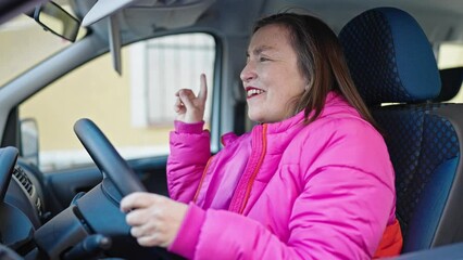 Sticker - Mature hispanic woman with grey hair sitting on car dancing at street