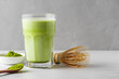 Matcha green tea iced latte with matcha powder and bamboo whisk. Cold refreshment summer drink