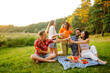 © maxbelchenko - Group of young people gathered in garden for picnic. Friends have fun and  drink beer. Vacation, picnic, friendship or holliday concept.