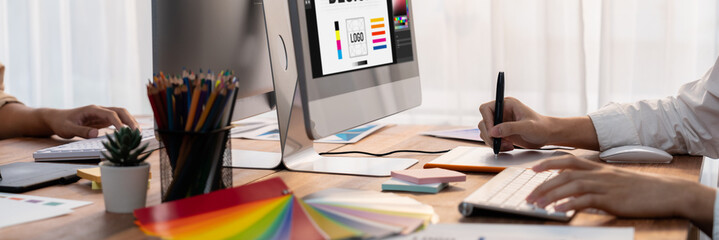 Poster - Graphic designer work on computer laptop and with graphic drawing pen while brainstorming unique design with professional graphic team in modern digital studio workplace. Panorama shot. Scrutinize