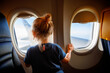 Adorable little girl traveling by an airplane. Child sitting by aircraft window and looking outside. Traveling with kids abroad. Family on summer vacations.
